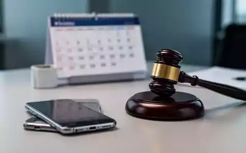 Ein Smartphone und ein Richterhammer auf einem Schreibtisch als Symbol für rechtliche Klärungen im Arbeitsrecht. - Foto: über boerse-global.de