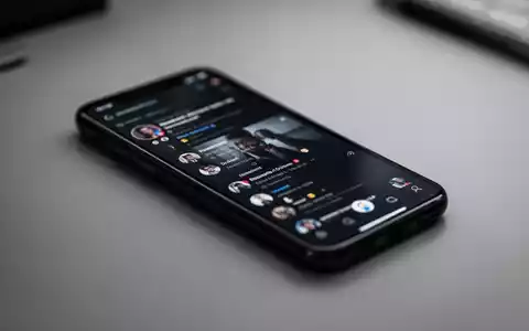 Ein Smartphone zeigt eine Social-Media-App auf einem Schreibtisch bei gedimmtem Licht. - Foto: über boerse-global.de
