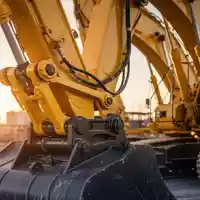 Moderner Hydraulikbagger auf einer Baustelle bei Sonnenuntergang, Fokus auf mechanische Bauteile und Stahlkonstruktion. - Foto: über boerse-global.de