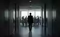 Silhouette eines Managers, der einen hell erleuchteten Konferenzraum verlässt, in dem sich andere Personen befinden. - Foto: über boerse-global.de
