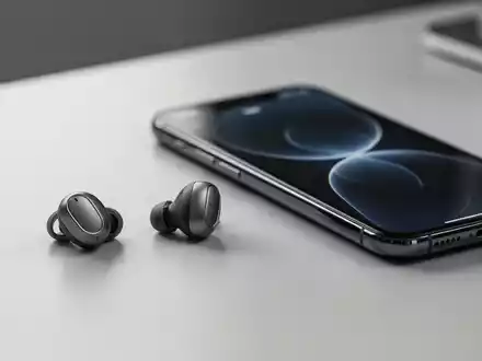 Moderne kabellose Ohrhörer auf einem eleganten Schreibtisch neben einem Smartphone, die die neue Moto Buds iOS-App darstellen. - Foto: über boerse-global.de