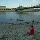 Unter der Freiheitsbrücke lässt sich's nun im Trockenen sitzen.  - Bild: Bela Szandelszky/AP/dpa