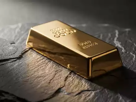 Ein glänzender Goldbarren auf einer dunklen Schieferplatte bei stimmungsvoller Beleuchtung. - Foto: über boerse-global.de