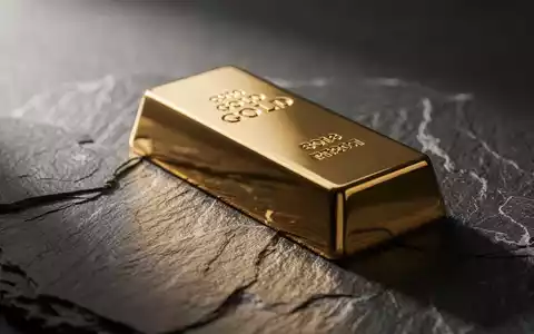 Ein glänzender Goldbarren auf einer dunklen Schieferplatte bei stimmungsvoller Beleuchtung. - Foto: über boerse-global.de