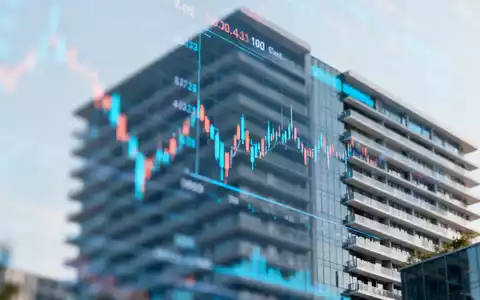 Abstrakte Finanzgrafik mit einem unscharfen Börsenticker vor einem modernen Immobiliengebäude. - Foto: über boerse-global.de