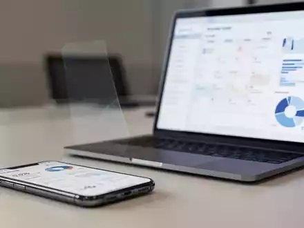 Ein Smartphone und ein Laptop mit einer digitalen Kalenderansicht auf dem Bildschirm in einer professionellen Büroumgebung. - Foto: über boerse-global.de
