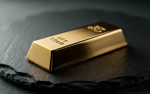 Ein glänzender Goldbarren auf einer dunklen Schieferplatte bei stimmungsvoller Beleuchtung. - Foto: über boerse-global.de