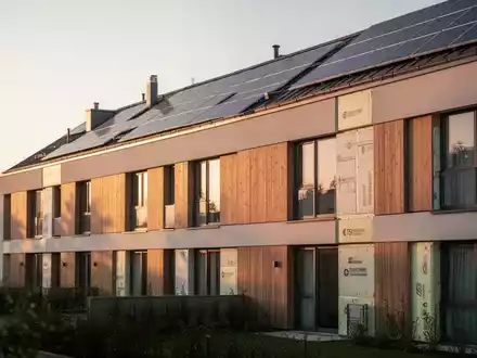 Modernes, energieeffizientes Wohngebäude mit Solaranlage bei Sonnenuntergang als Symbol für Gebäudeförderung. - Foto: über boerse-global.de