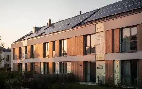 Modernes, energieeffizientes Wohngebäude mit Solaranlage bei Sonnenuntergang als Symbol für Gebäudeförderung. - Foto: über boerse-global.de