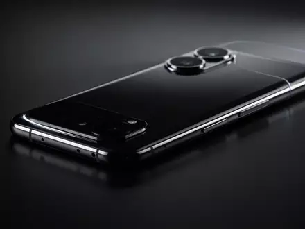 Schlankes Smartphone-Silhouette mit markantem Kameramodul auf dunkler, reflektierender Fläche. - Foto: über boerse-global.de