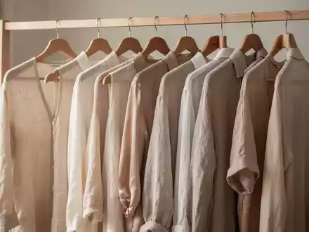 Minimalistisch gestaltete Garderobe mit hochwertigen Kleidungsstücken in neutralen Farben und natürlichen Materialien. - Foto: über boerse-global.de