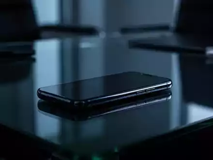 Ein modernes Smartphone auf einem dunklen Schreibtisch, das die Themen Datenschutz und digitale Sicherheit symbolisiert. - Foto: über boerse-global.de