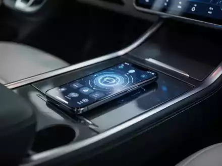 Ein Smartphone mit digitaler Fahrzeugschlüssel-App in der Mittelkonsole eines modernen Elektroautos. - Foto: über boerse-global.de