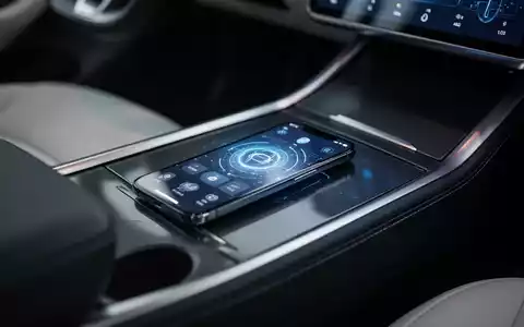 Ein Smartphone mit digitaler Fahrzeugschlüssel-App in der Mittelkonsole eines modernen Elektroautos. - Foto: über boerse-global.de