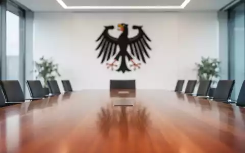 Modernes Büro im Bundeskanzleramt mit einem Konferenztisch vor einem unscharfen Hintergrund eines Staatswappens. - Foto: über boerse-global.de