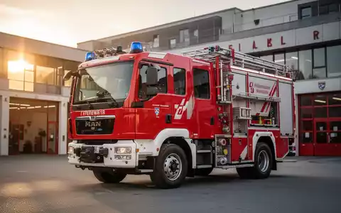 Ein modernes rotes Löschfahrzeug vom Typ LF 10 vor einem Feuerwehrhaus in Bayern bei Tageslicht. - Foto: über boerse-global.de