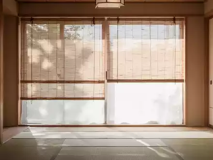 Ein minimalistisch gestalteter japanischer Wohnraum mit hellen Holzelementen und halb herabgelassenen Bambusrollos. - Foto: über boerse-global.de