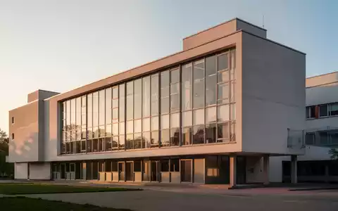Die ikonische Glasfassade des Bauhausgebäudes in Dessau bei klarem Licht, die die minimalistische Architektur betont. - Foto: über boerse-global.de