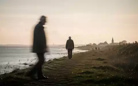 Eine ländliche Küstenlandschaft in Nordfriesland mit einer unscharfen Silhouette eines älteren Menschen beim Spaziergang. - Foto: über boerse-global.de