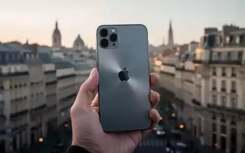 Moderne iPhone in einer Hand gehalten mit verschwommenem europäischen Stadtbild im Hintergrund. - Foto: über boerse-global.de
