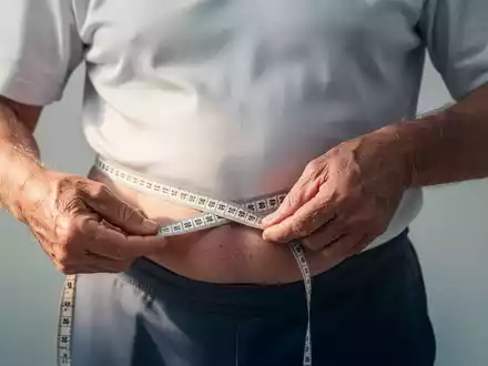 Eine Person über 50 Jahre misst ihren Taillenumfang mit einem Maßband, symbolisch für das Gesundheitsrisiko durch Bauchfett. - Foto: über boerse-global.de
