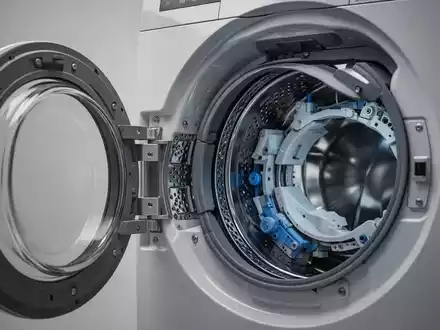 Nahaufnahme einer geöffneten Waschmaschine mit sichtbaren technischen Bauteilen als Symbol für professionelle Reparaturen. - Foto: über boerse-global.de