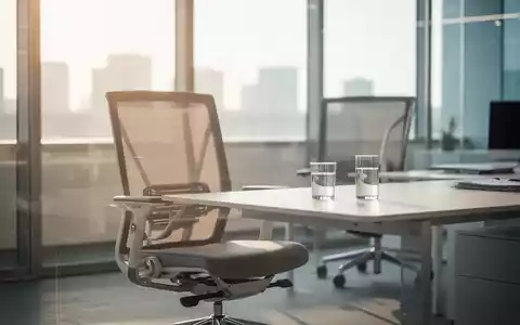 Ein moderner, leerer Büroarbeitsplatz mit einem ergonomischen Stuhl und einem Glas Wasser bei hellem Tageslicht. - Foto: über boerse-global.de