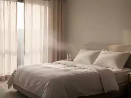 Ein minimalistisch eingerichtetes, kühles Schlafzimmer mit leichter Bettwäsche und zugezogenen Vorhängen an einem Sommertag. - Foto: über boerse-global.de