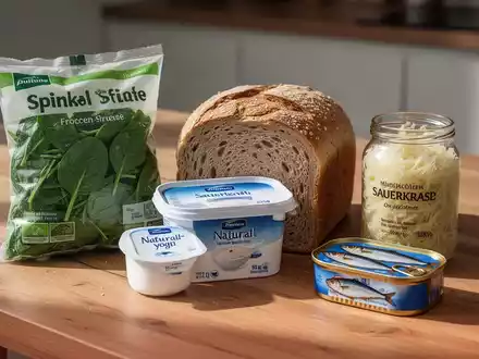Eine Auswahl gesunder und kostengünstiger Lebensmittel wie Tiefkühlgemüse, Vollkornbrot, Sauerkraut und Sardinen auf einem Holztisch. - Foto: über boerse-global.de