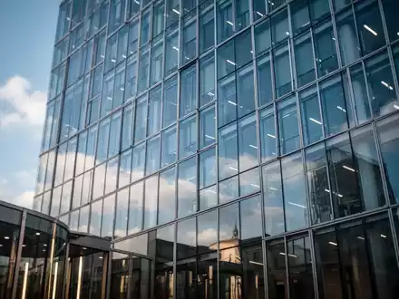 Moderne Glasfassade eines Bürogebäudes in Berlin unter blauem Himmel als Symbol für Finanzpolitik. - Foto: über boerse-global.de