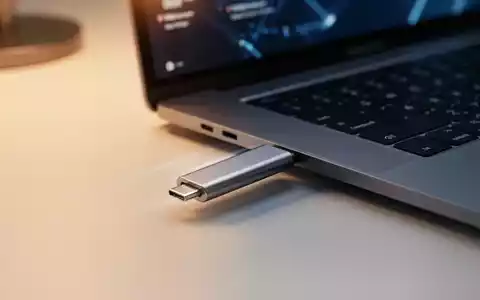 Ein USB-Stick steckt in einem modernen Laptop, symbolisch für plattformübergreifende IT-Tools zwischen macOS und Windows. - Foto: über boerse-global.de