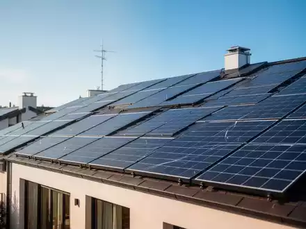 Moderne Solaranlagen auf einem Hausdach unter blauem Himmel als Symbol für die Energiewende und Netzentgelte. - Foto: über boerse-global.de