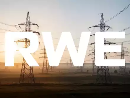 Hochspannungsmasten in einer weitläufigen Landschaft bei Sonnenaufgang als Symbol für Energieinfrastruktur. - Foto: über boerse-global.de