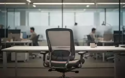 Ein leerer Büroarbeitsplatz mit einem ergonomischen Stuhl vor dem Hintergrund eines modernen, verschwommenen Büros. - Foto: über boerse-global.de