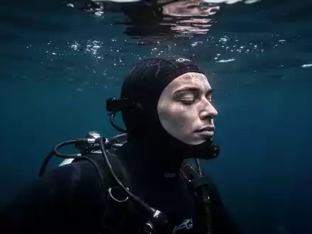 Ein konzentrierter Freitaucher im tiefblauen Wasser, der eine meditative Haltung einnimmt. - Foto: über boerse-global.de