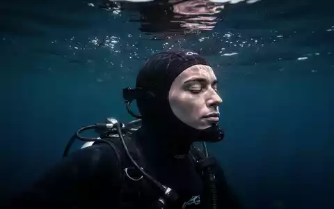 Ein konzentrierter Freitaucher im tiefblauen Wasser, der eine meditative Haltung einnimmt. - Foto: über boerse-global.de