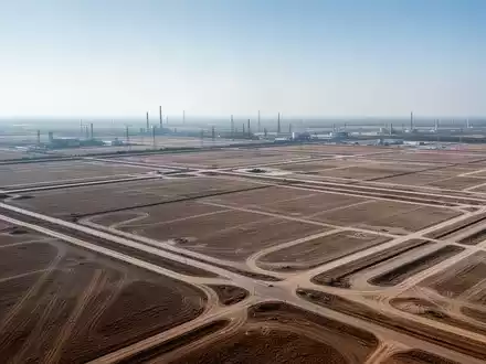 Weitläufiges, unbebautes Industriegelände bei klarem Tageslicht aus der Vogelperspektive. - Foto: über boerse-global.de