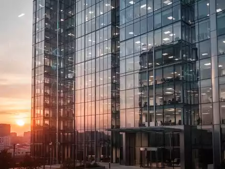Moderne Glasfassade eines Bürogebäudes bei Sonnenuntergang als Symbol für Finanzthemen. - Foto: über boerse-global.de