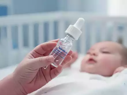 Nahaufnahme einer medizinischen Pipettenflasche für Vitamin-D-Präparate in der Hand eines Säuglings. - Foto: über boerse-global.de