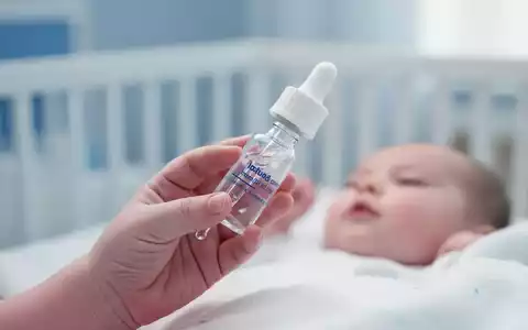 Nahaufnahme einer medizinischen Pipettenflasche für Vitamin-D-Präparate in der Hand eines Säuglings. - Foto: über boerse-global.de