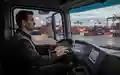 Innenansicht einer modernen Logistikfahrzeugkabine mit Blick auf einen beleuchteten Containerterminal. - Foto: über boerse-global.de