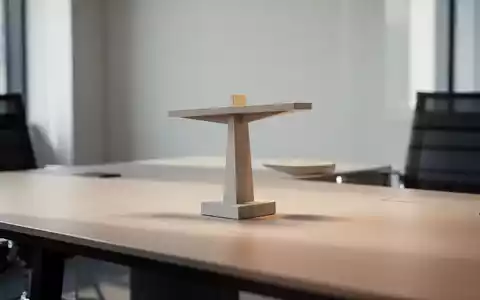 Ein minimalistischer, moderner Arbeitsplatz mit Fokus auf eine neutrale, architektonische Balance-Skulptur. - Foto: über boerse-global.de