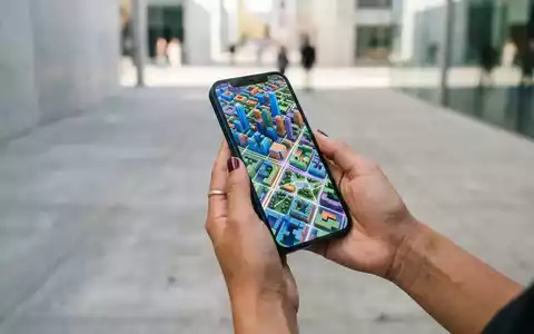 Person hält ein modernes Smartphone mit einer detaillierten 3D-Kartenansicht in einer urbanen Umgebung. - Foto: über boerse-global.de