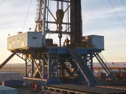 Ein industrieller Bohrturm bei Sonnenuntergang in einer weitläufigen Landschaft als Symbol für die Wasserstoffexploration. - Foto: über boerse-global.de