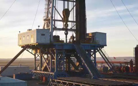 Ein industrieller Bohrturm bei Sonnenuntergang in einer weitläufigen Landschaft als Symbol für die Wasserstoffexploration. - Foto: über boerse-global.de