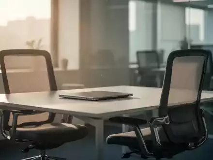 Ein leerer moderner Büroarbeitsplatz mit geschlossenem Laptop vor einem Fenster, das sanftes Tageslicht in den Raum lässt. - Foto: über boerse-global.de
