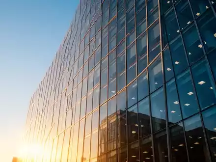 Moderne Glasfassade eines Bürogebäudes bei Sonnenuntergang als Symbol für wirtschaftlichen Erfolg - Foto: über boerse-global.de