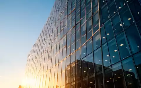 Moderne Glasfassade eines Bürogebäudes bei Sonnenuntergang als Symbol für wirtschaftlichen Erfolg - Foto: über boerse-global.de