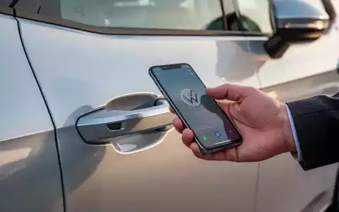 Eine Hand hält ein Smartphone nahe an den Türgriff eines modernen Volkswagen ID.3 Neo Elektroautos. - Foto: über boerse-global.de