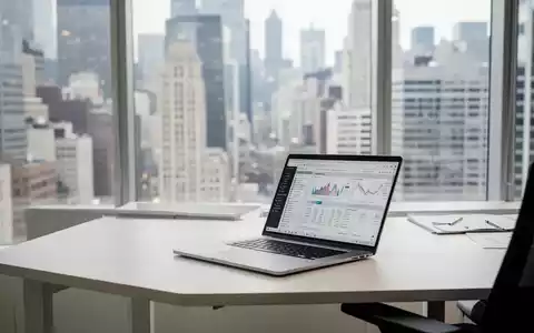Ein moderner, heller Büroarbeitsplatz mit Laptop vor einem verschwommenen Finanzviertel im Hintergrund. - Foto: über boerse-global.de